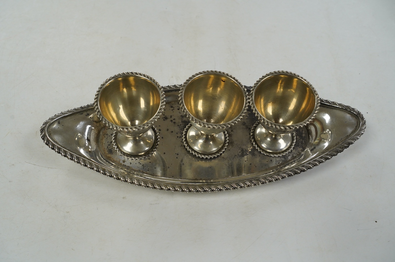 A late Victorian silver egg cruet, with three cups on a navette shaped stand, Chester, 1898, 25.8cm, 10.9oz. Condition - poor to fair